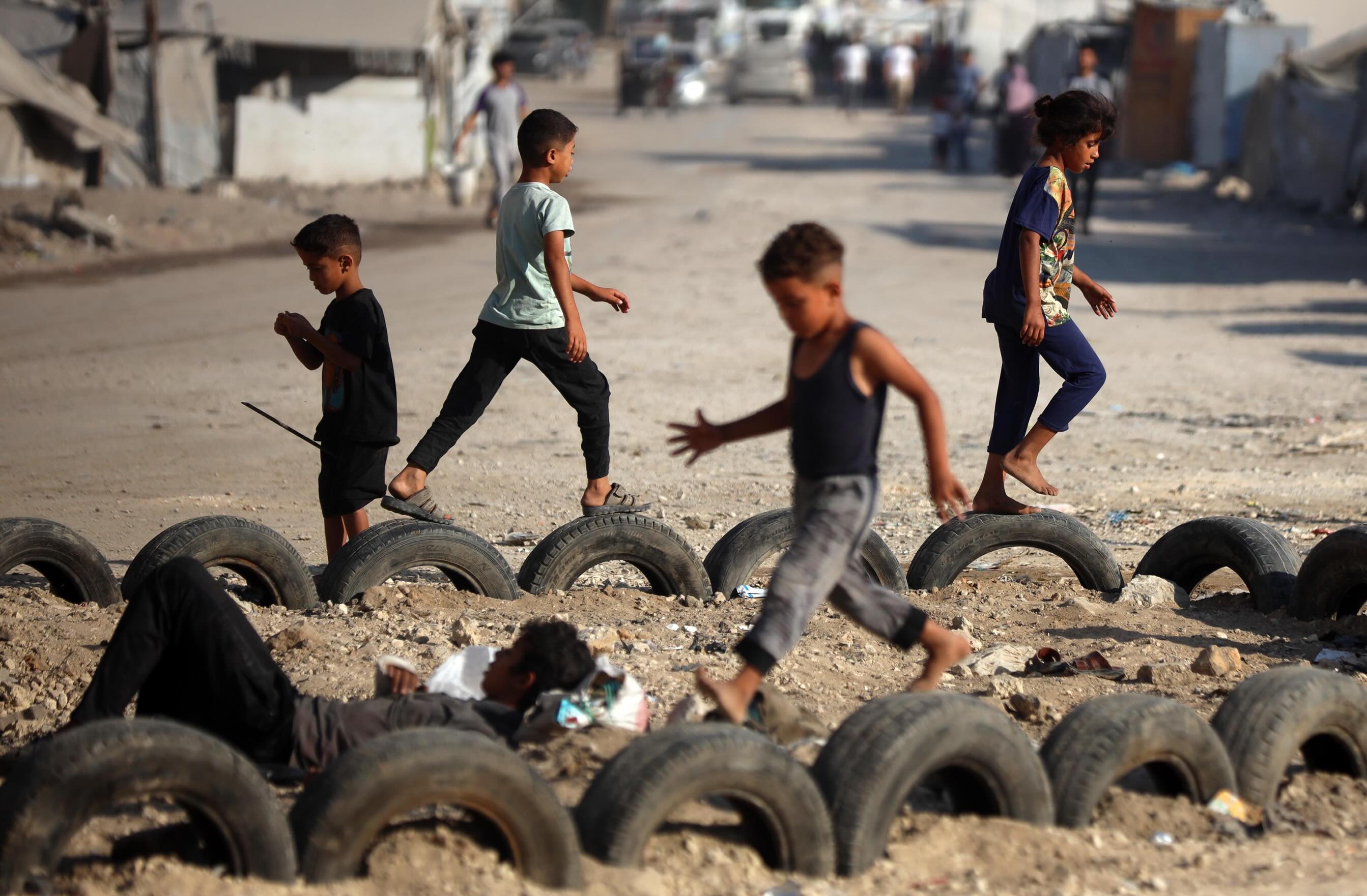 https://newyorkwarcrimes.com/media/pages/gaza-s-orphan-generation/1e465dfb85-1784150420/6-bw-children-displaced-palestinian-children-play-in-the-street-near-their-tents-west-of-gaza-city-on-june-24-2026-photo-by-majd.jpg